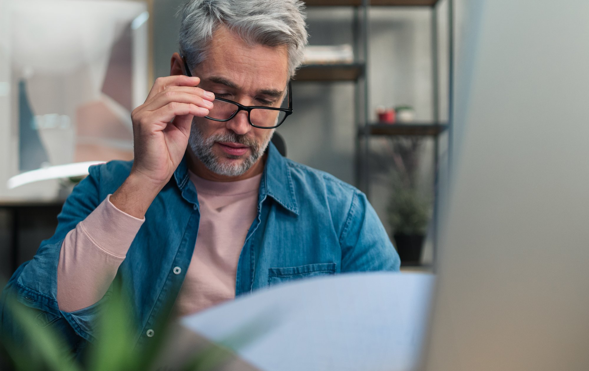 Man holding glasses and reading