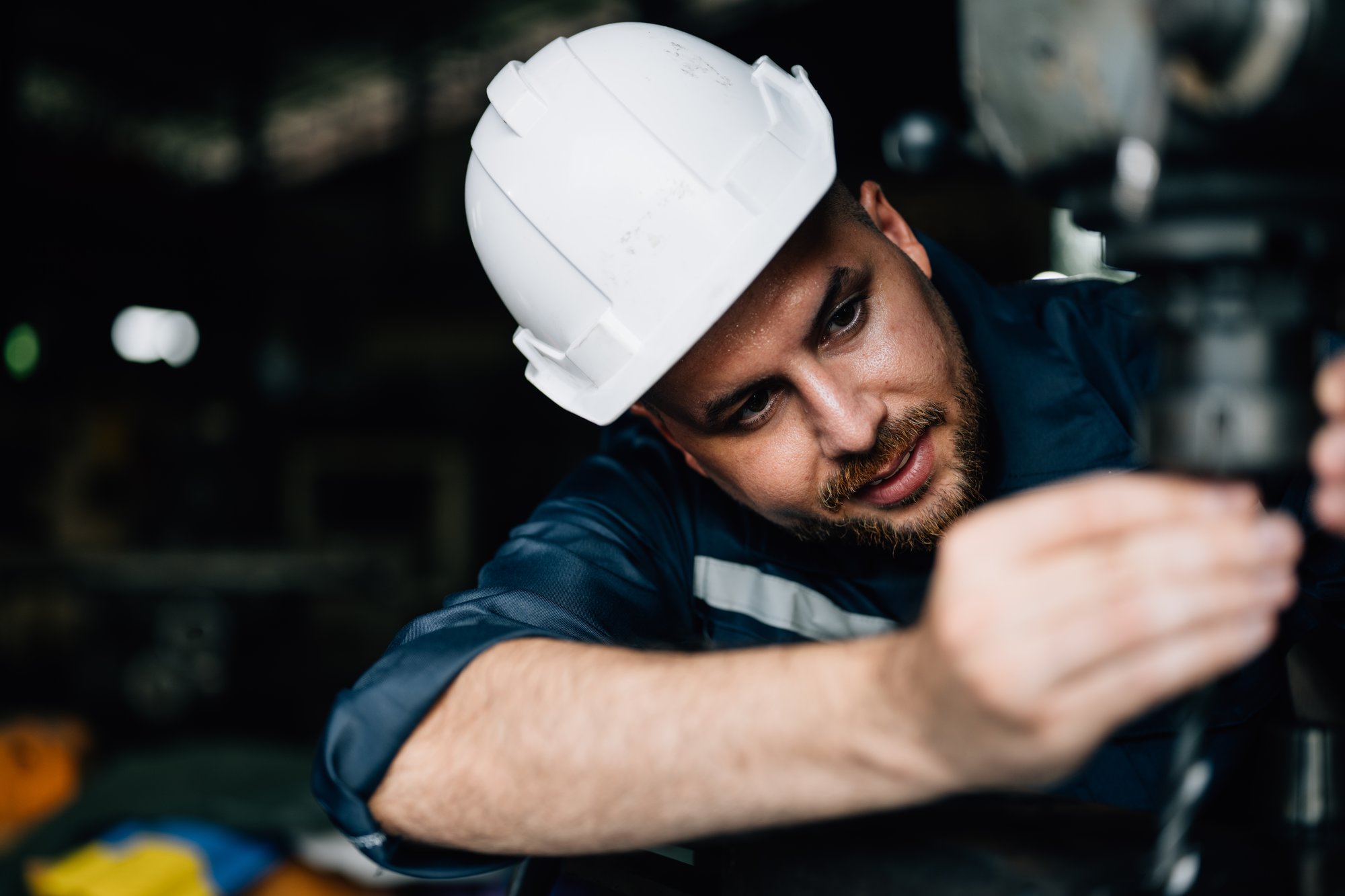 Machinist servicing a milling machine in a machine shop installing a drill